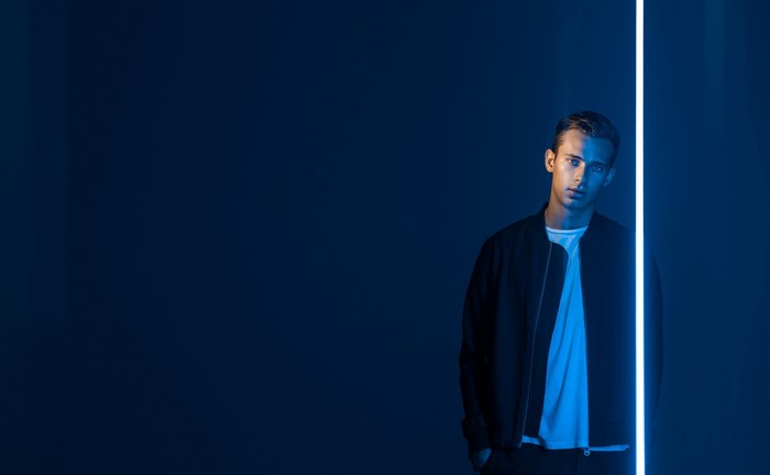 Musician Flume standing by a blue light
