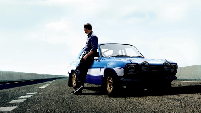 Paul Walker leaning on a blue Fast and Furious car