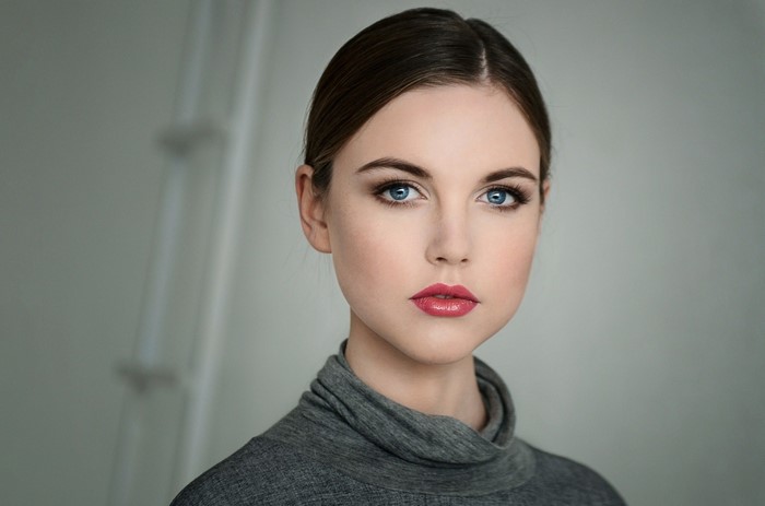 Woman with blue eyes and pink lips wearing a grey turtleneck