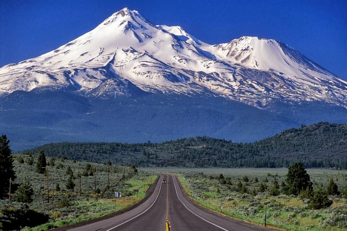 Snow-capped mountain range with a road leading towards it