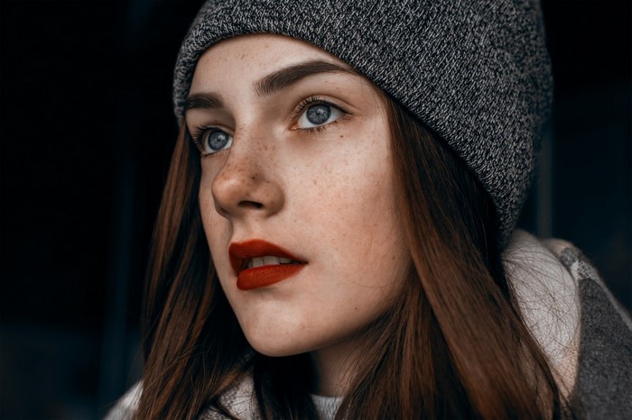 Woman with freckles wearing a beanie and red lipstick