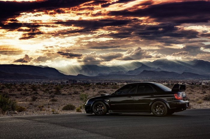 Black Subaru Impreza WRX STi in desert landscape at sunset