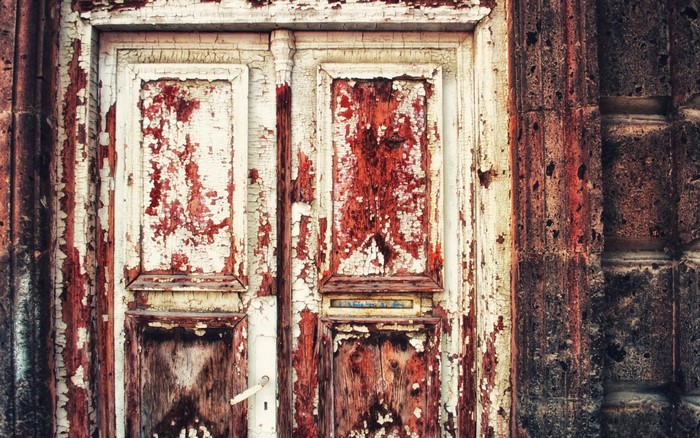 Peeling paint on an old wooden door with a stone wall