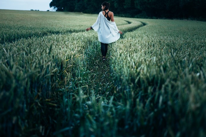 Woman walking through a wheat field at dusk