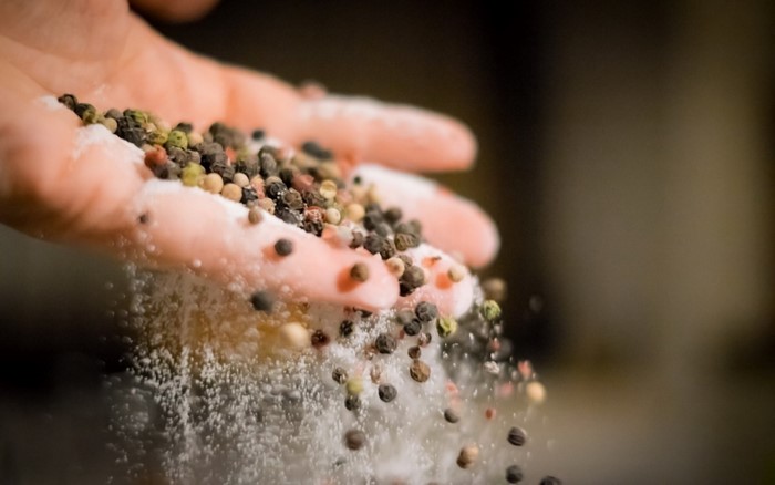 Hand pouring peppercorns and salt