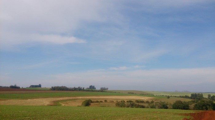 Rolling hills and agricultural fields under a cloudy sky