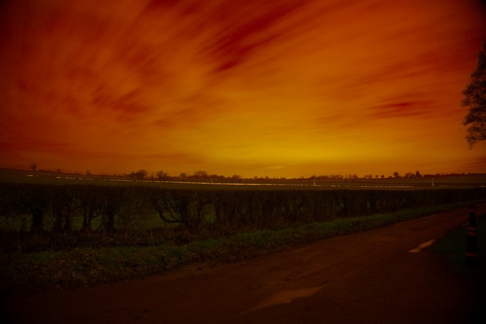 Orange sky over a field and road