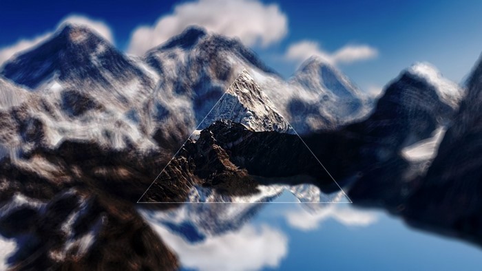 Snow-capped mountains reflected in water with a triangle overlay