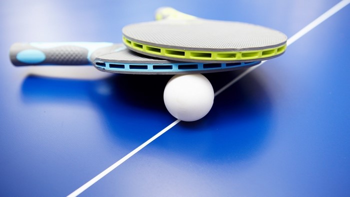 Table tennis paddles and ball on blue table
