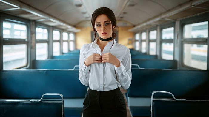 Woman in white shirt and glasses on a train