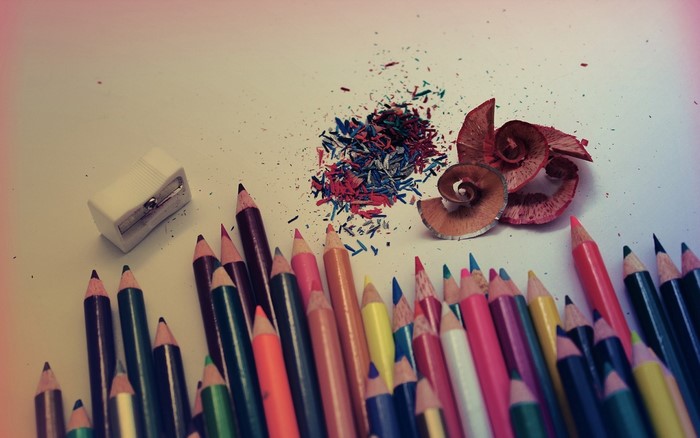 Colored pencils, sharpener, and shavings on a white surface