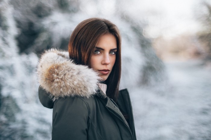 Woman in fur-lined winter coat in snowy forest