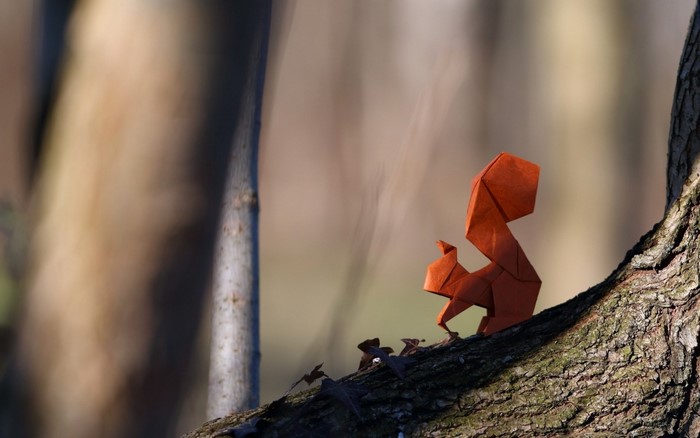 Origami squirrel on a tree branch in autumn