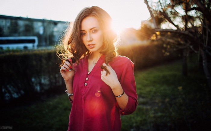 Woman in red shirt posing outdoors at sunset