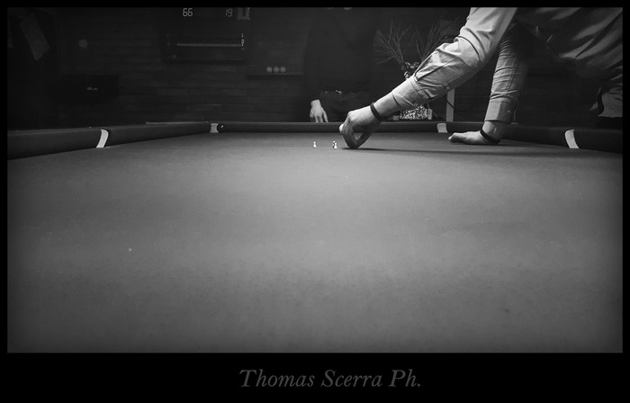 Man playing billiards with small pawns on a pool table