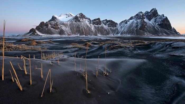 Snow-capped mountains over black sand dunes in Iceland