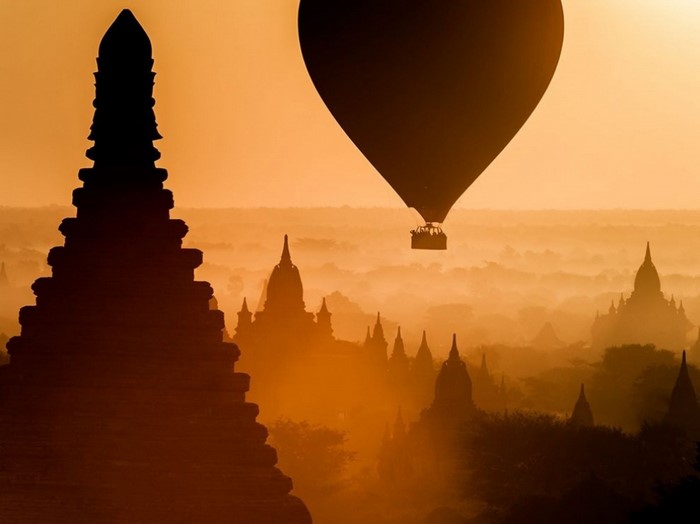 Hot air balloon over ancient temples at sunrise