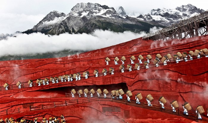 Performers with baskets on red terraces with snowy mountains