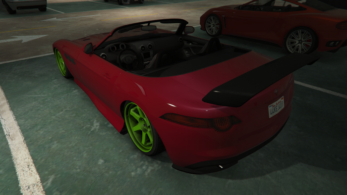 Red convertible sports car with green wheels in a parking lot