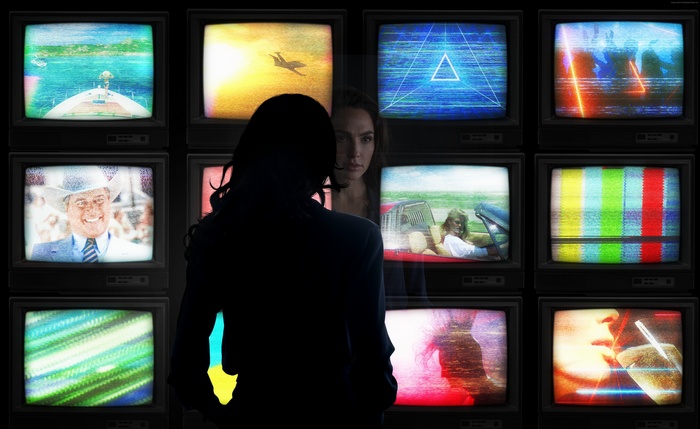 Gal Gadot in front of multiple vintage televisions