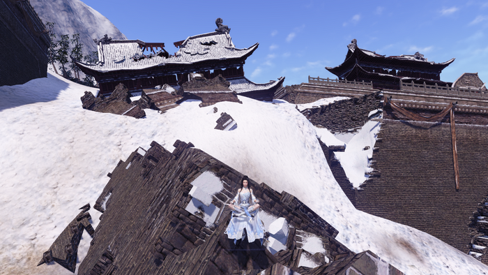 A person in white robes meditates on a snowy mountain ruin