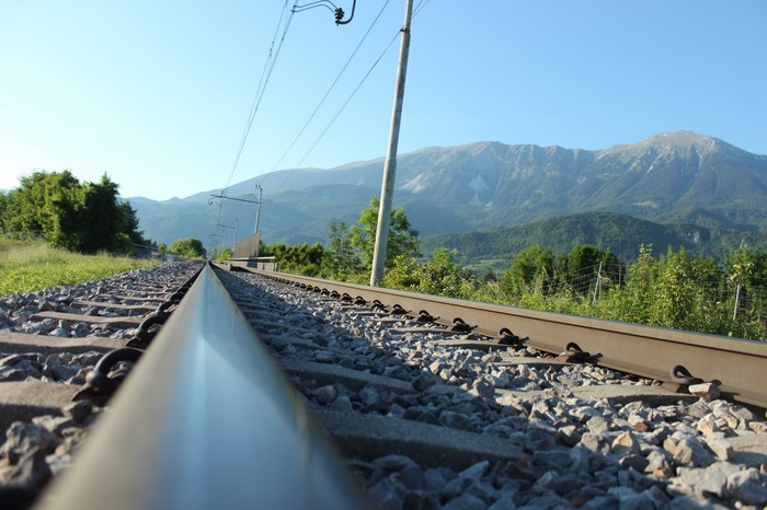 Railway tracks leading to mountains with electric wires