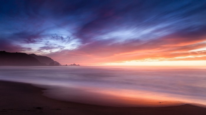 Sunset over the ocean with colorful clouds and waves