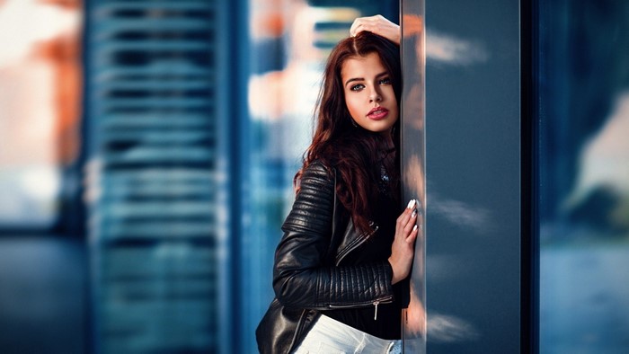 Woman in leather jacket leaning against a column