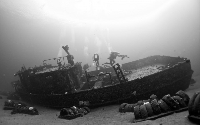 Divers explore a sunken shipwreck on the ocean floor