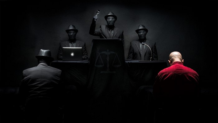 People in dark suits and hats in a courtroom setting