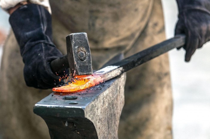Blacksmith hammering glowing metal on anvil