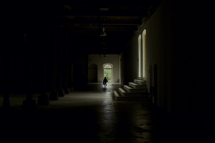 Silhouette of a person walking down a dark hallway towards a window