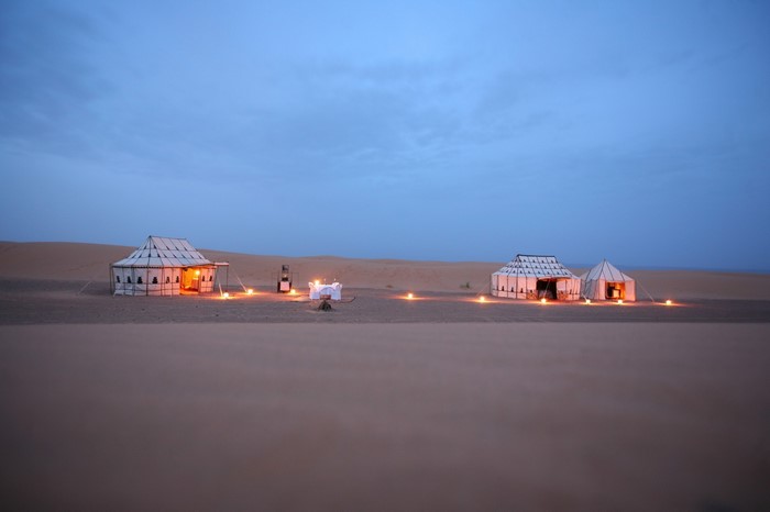 Desert camp with tents and dining setup at dusk