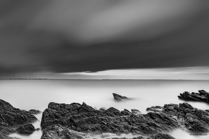 Monochrome seascape with rocks and long exposure clouds