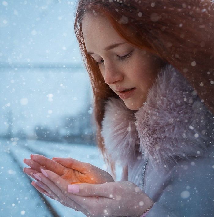 Woman with red hair in the snow holding light
