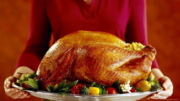 A person holding a platter with a roasted turkey