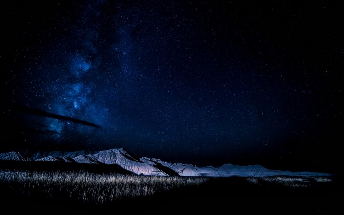 Night sky over mountains and grass