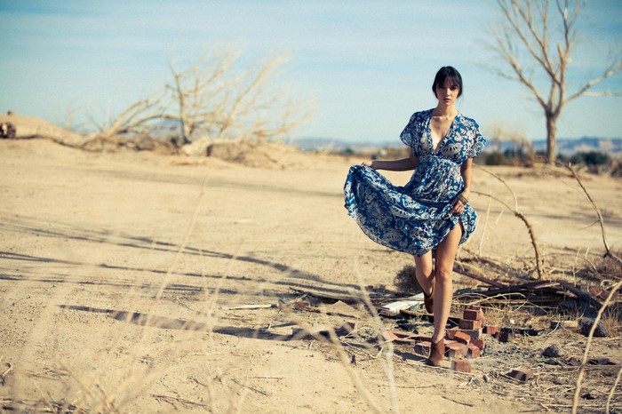 Woman in Blue Dress Walking on Sandy Desert