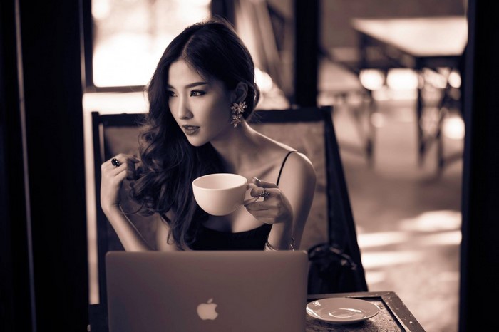 Sepia portrait of a woman with a coffee cup and laptop