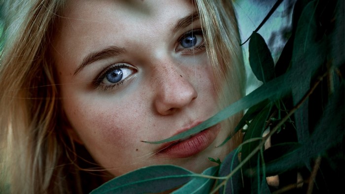 Close up portrait of a young woman with blue eyes and freckles