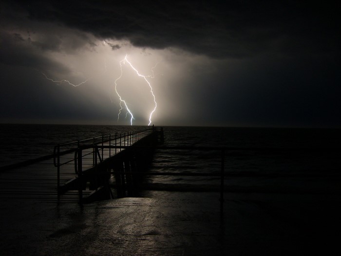 Lightning strikes over a pier at night