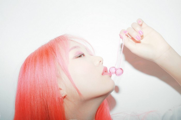 Woman with pink hair holding cherry earrings