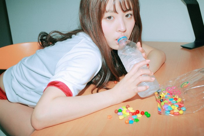 Asian girl drinking water from bottle with candy