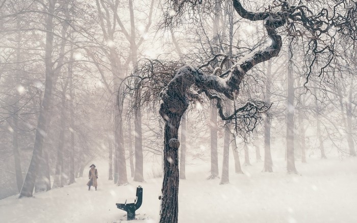 Person in a trench coat walking in a snowy park