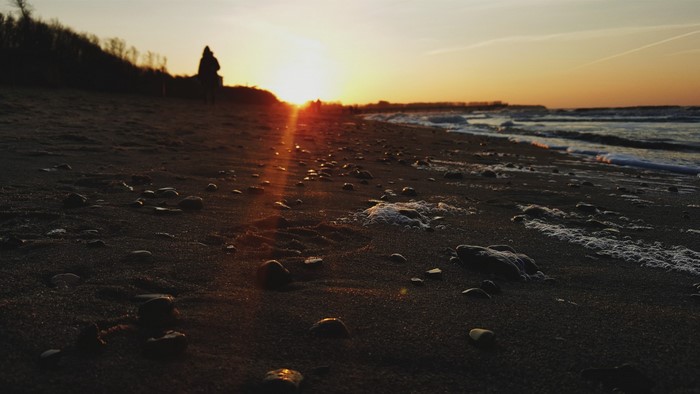 Sunset over a pebble beach with a lone figure