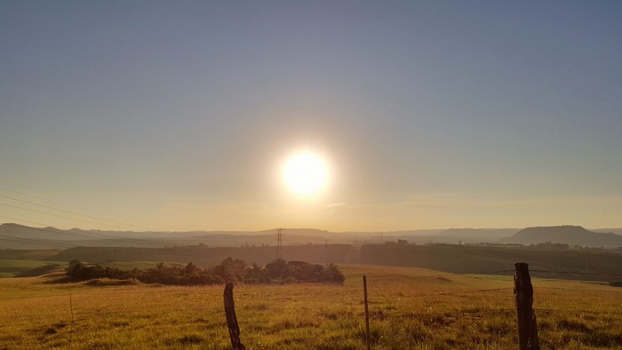 Sunset over a grassy field with rolling hills