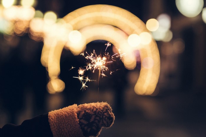 Hand holding a sparkler with bokeh lights