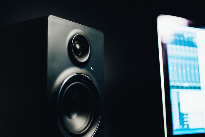 Black studio monitor speaker next to a computer screen