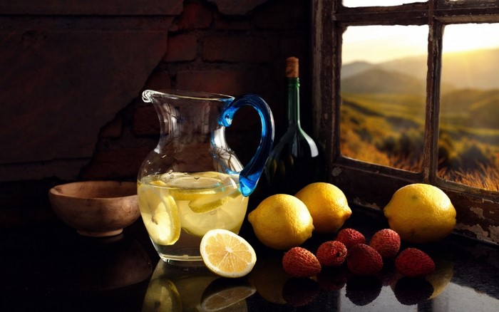 Still life of lemonade, lemons, and berries by a window