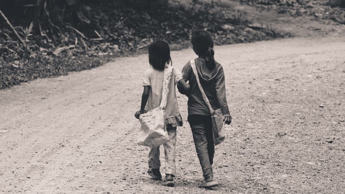 Two children walking on a dirt path